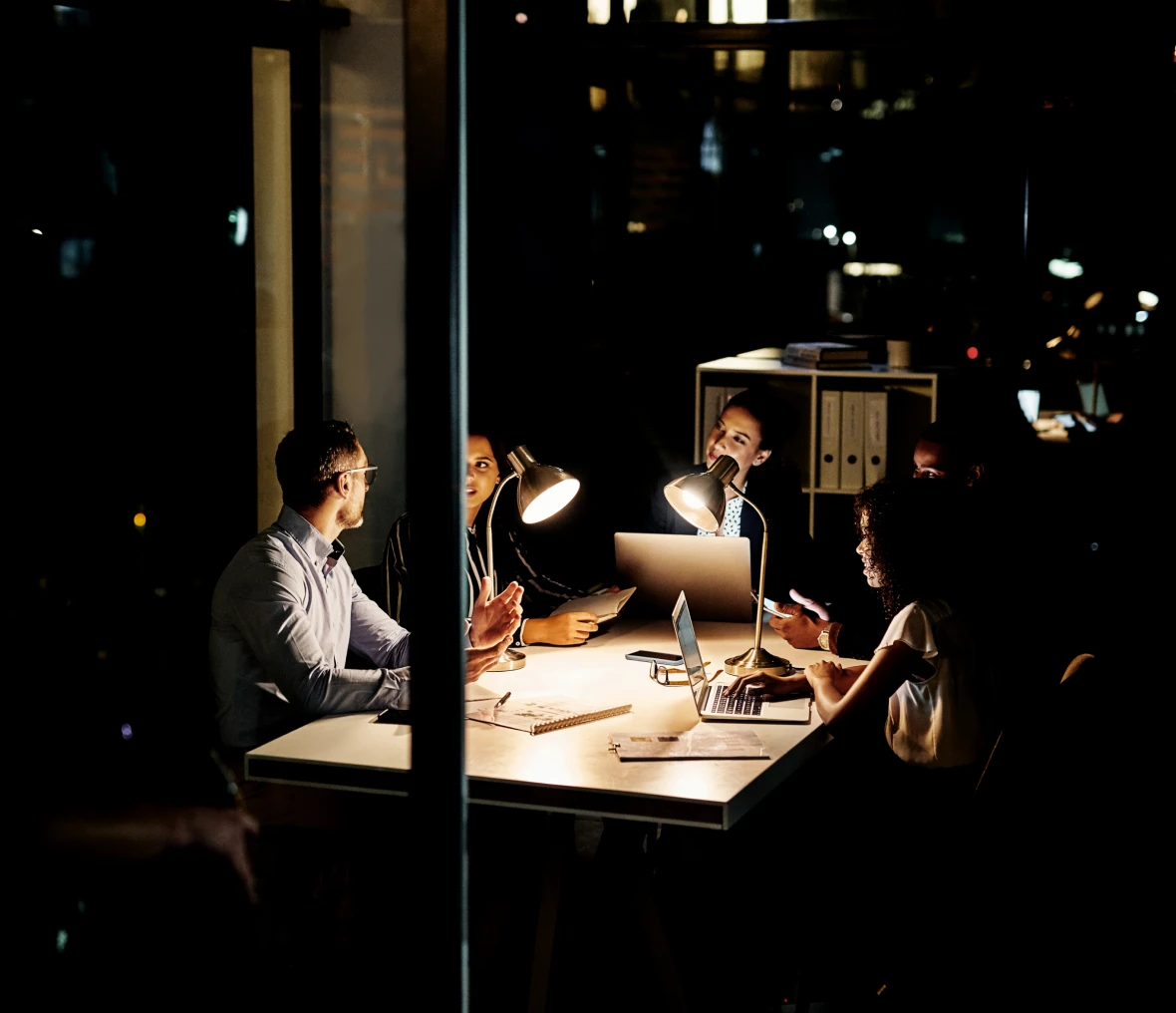 Colleagues collaborating over laptops in darkness